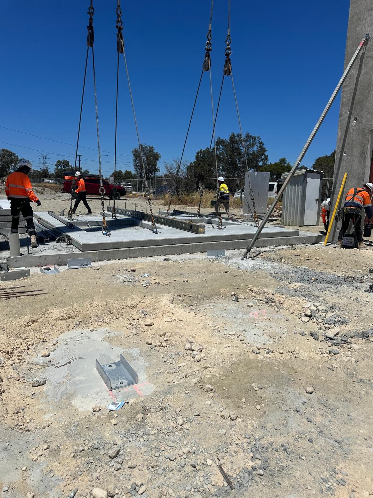 Crane rigging lifting a precast panel with workers in hi-vis